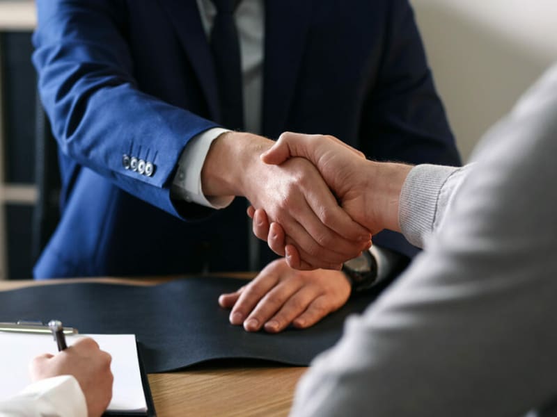 Gentlemen, shaking hands over a desk